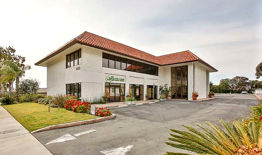 The funded Newport Beach property: a white two-storey commercial building with a red tile roof and a landscaped parking court.